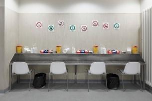 Tisch mit vier Stühlen und Piktogramme mit Verhaltensregeln in Drogenabgabestelle. 