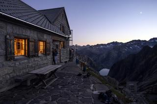 Guetss enjoy the sunset from the cabin stands Gelmerhuette during a beautiful summer sunset.