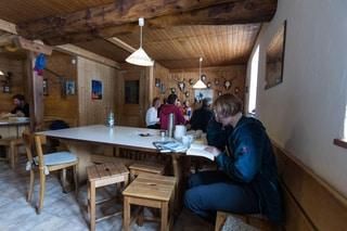 Guests sitting and relaxing in the recreation room of the Saoseo mountain hut.